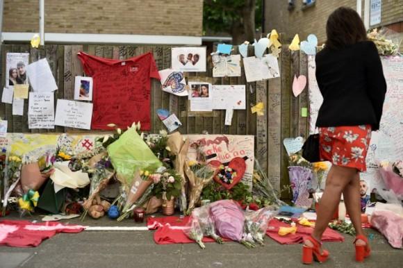 A woman looks at flowers, tributes and messages left for the victims of the fire at the Grenfell apartment tower in North Kensington, London, Britain, June 23, 2017. (Reuters/Hannah McKay)
