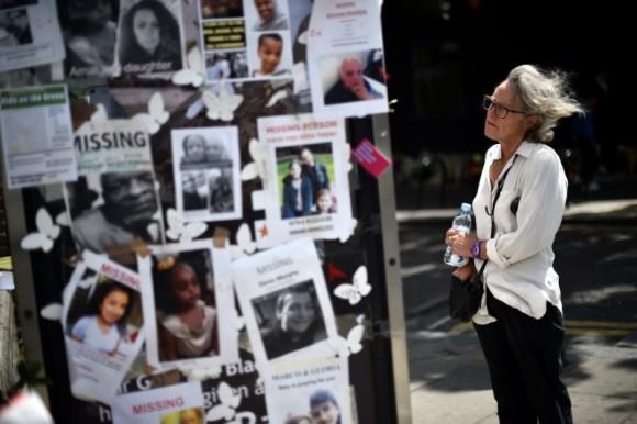 A woman looks at pictures of the victims of the fire at the Grenfell apartment tower stuck to a telephone box in North Kensington, London, Britain, June 23, 2017. (Reuters/Hannah McKay)