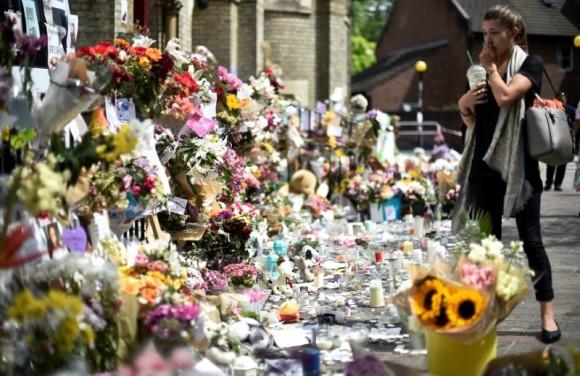 A woman looks at flowers, tributes and messages left for the victims of the fire at the Grenfell apartment tower in North Kensington, London, Britain, June 23, 2017. (Reuters/Hannah McKay)