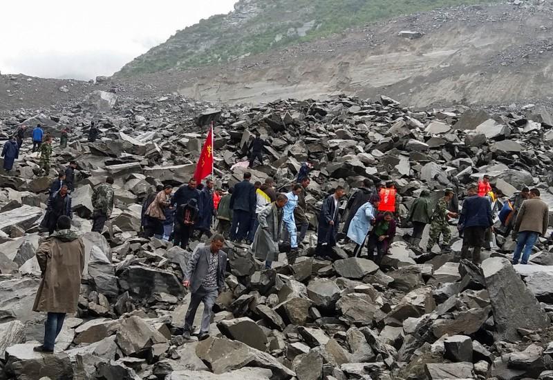 People search for survivors at the site of a landslide that destroyed some 40 households, where more than 100 people are feared to be buried, according to local media reports, in Xinmo Village, China on June 24, 2017. (REUTERS/Stringer)