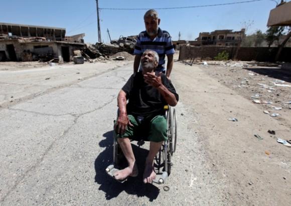 A displaced Iraqi man who fled from clashes pushes an old man in a wheelchair in the Old City of Mosul, Iraq June 24, 2017. (Reuters/Azad Lashkari)