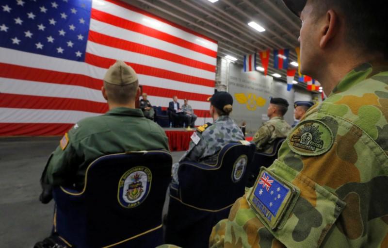 A member of the Australian Army sits in the audience alongside a U.S. flag as the backdrop of a ceremony marking the start of Talisman Saber 2017, a biennial joint military exercise between the United States and Australia, aboard the USS Bonhomme Richard amphibious assault ship on the the Pacific Ocean off the coast of Sydney, Australia, June 29, 2017. (REUTERS/Jason Reed)