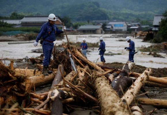 Police officers walk on woody debris which were swept by heavy rain as they conduct rescue and search operation in Asakura, Fukuoka Prefecture, Japan July 8, 2017. (Reuters/Issei Kato)