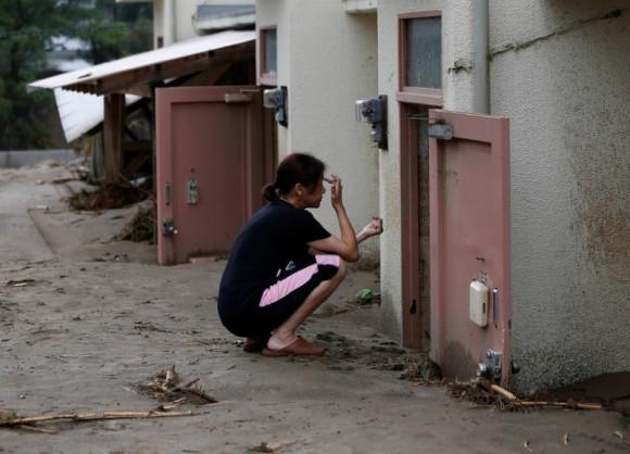 A local resident sits in front of mud covered door of her room as she looks for her personal belongings at an area hit by heavy rain in Asakura, Fukuoka Prefecture, Japan July 8, 2017. (Reuters/Issei Kato)