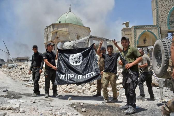 A member of the Iraqi Counter-Terrorism Service (CTS) raises the victory gesture as others hold upside-down the black flag of the Islamic State (IS) group, outside the destroyed Al-Nuri Mosque in the Old City of Mosul, after the area was retaken from ISIS, on June 30, 2017.<br/>(FADEL SENNA/AFP/Getty Images)