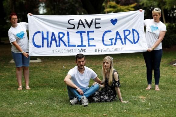 Connie Yates and Chris Gard, pose for photographers as supporters hold a banner before delivering a petition to Great Ormond Street Hospital in central London on July 9, 2017. (Peter Nicholls/Reuters)