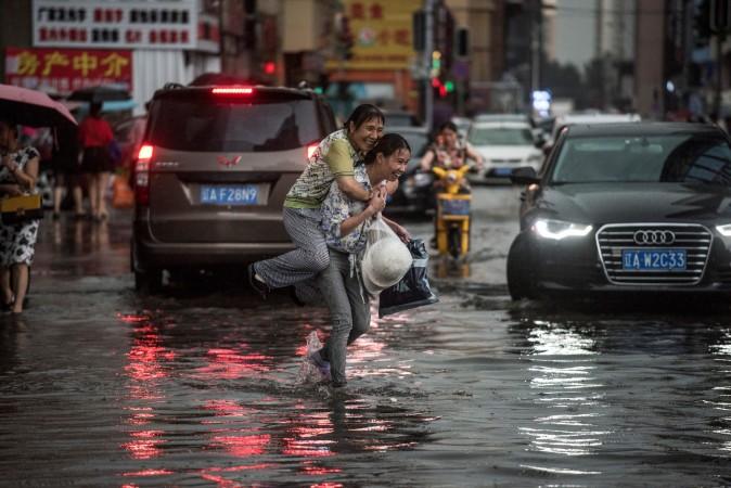 A woman holds an elderly woman on her back to cross a flooded street after heavy rain in Shenyang, China, on July 14, 2017. (FRED DUFOUR/AFP/Getty Images)