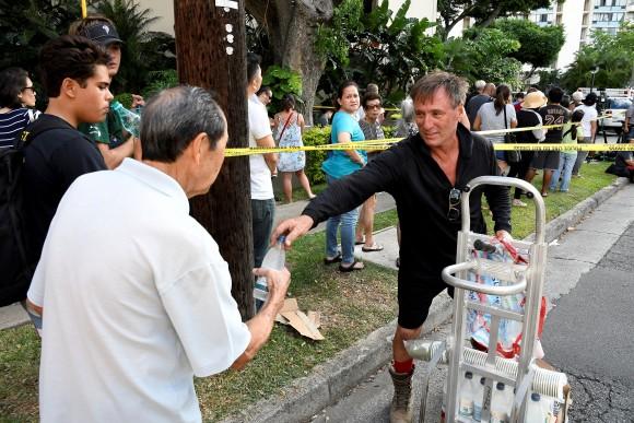 James Graffis hands out bottled water to residents of the Marco Polo apartment building after a fire broke out in it in Honolulu, Hawaii, July 14, 2017. (Reuters/Hugh Gentry)