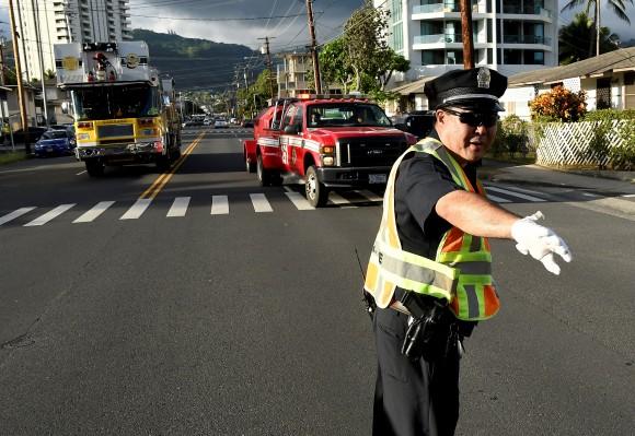 A police officer directs a fire truck to the Marco Polo apartment building after a fire broke out in it in Honolulu, Hawaii, July 14, 2017. (Reuters/Hugh Gentry)