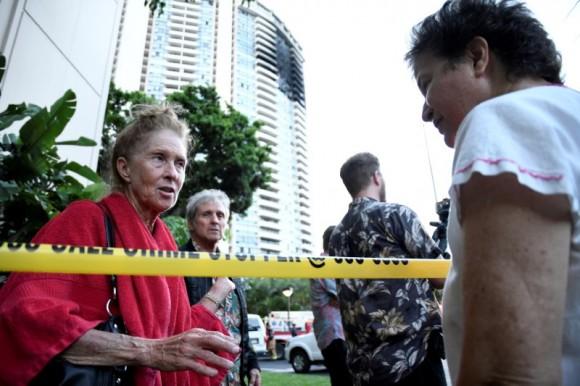 Karen Hastings (L), who was evacuated from the floors where the fire broke out at Marco Polo apartment building, talks with another resident, in Honolulu, Hawaii, July 14, 2017. (Reuters/Hugh Gentry)