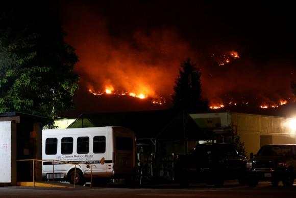 Flames from the Detwiler fire burn on a hill near the John C. Fremont Hospital in Mariposa, California, U.S., July 18, 2017. (Reuters/Stephen Lam)