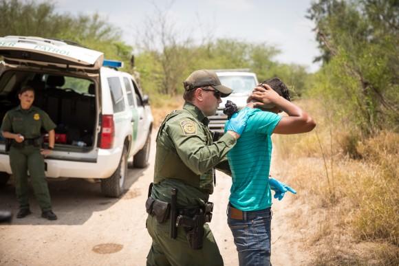 A Border Patrol agent pats down a Honduran man who has just crossed the Rio Grande from Mexico in Hidalgo County, Texas, on May 26, 2017. (Benjamin Chasteen/The Epoch Times)
