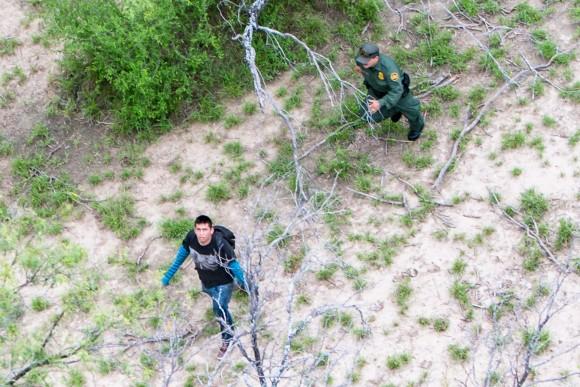An illegal alien looks up at a Customs and Border Protection helicopter while he is being pursued by a Border Patrol agent after trying to evade capture, near Salineño, Texas, on May 30, 2017. (Benjamin Chasteen/The Epoch Times)