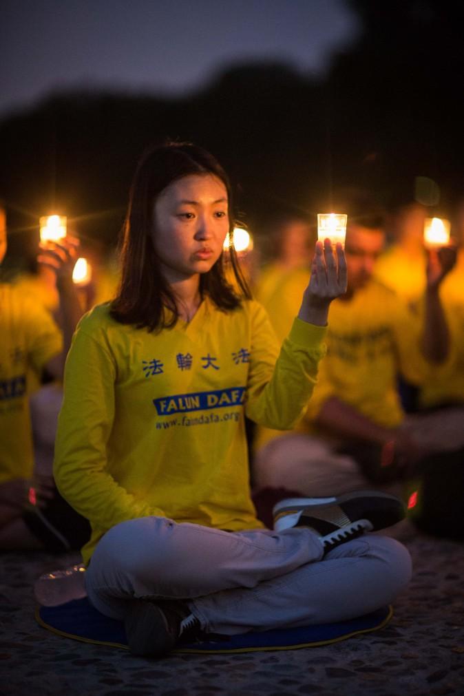 A woman joins Falun Gong practitioners at a candlelight vigil at the Lincoln Memorial in Washington on July 20, 2017, to honor the lives lost since the Chinese regime launched the persecution eighteen years ago. (Benjamin Chasteen/The Epoch Times)