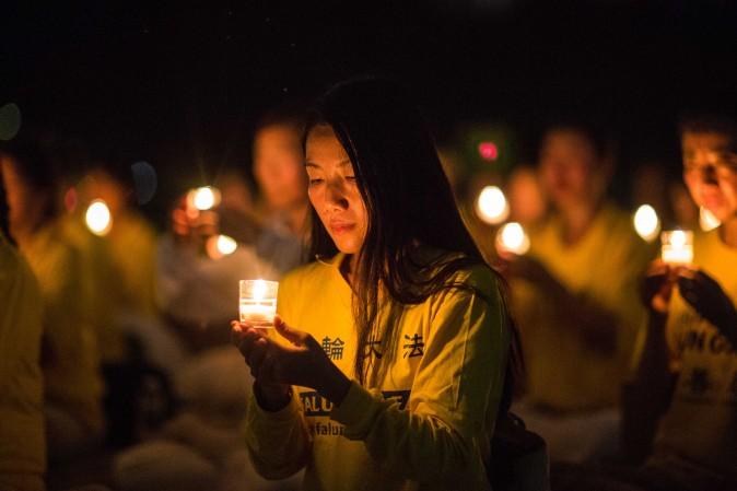 A woman joins Falun Gong practitioners in a candlelight vigil at Lincoln Memorial in Washington on July 20, 2017, to honor the lives lost since the Chinese regime launched the persecution eighteen years ago. (Benjamin Chasteen/The Epoch Times)