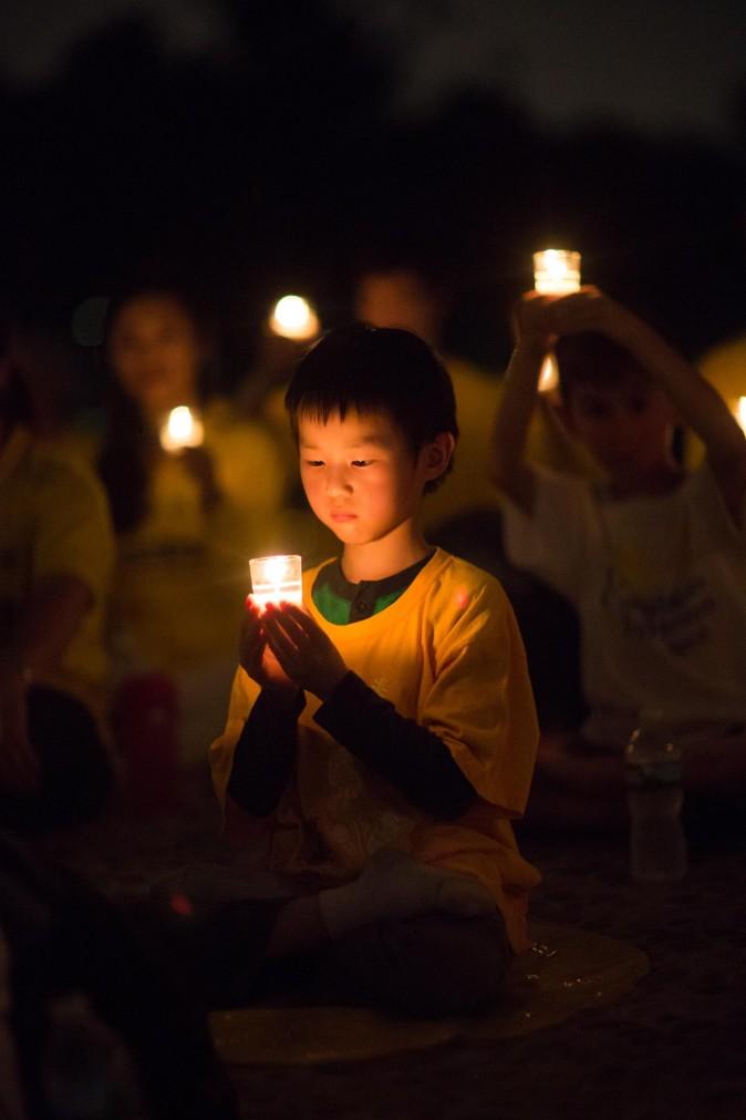 A little boy joins Falun Gong practitioners at a candlelight vigil at the Lincoln Memorial in Washington on July 20, 2017, to honor the lives lost since the Chinese regime launched the persecution eighteen years ago. (Benjamin Chasteen/The Epoch Times)