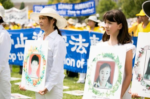 Two Falun Gong practitioners protest the brutal persecution and deaths of Falun Gong practitioners in China at a rally in Washington, D.C. on July 20. They are holding the photos of two victims of the persecution. (Lisa Fan/ Epoch Times)