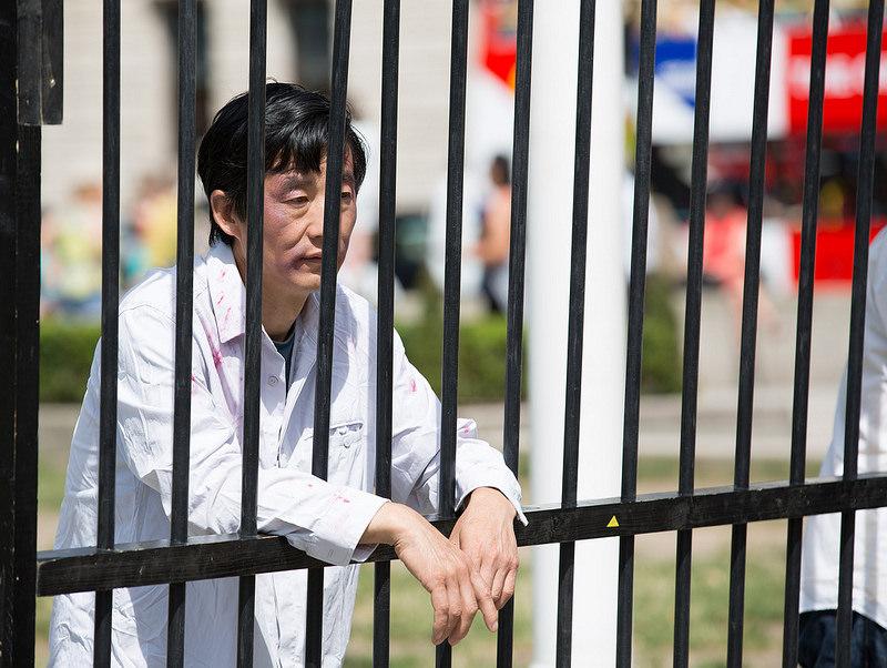 A Falun Gong practitioner enacts being illegally imprisoned in China as part of a peaceful protest outside Parliament Square on 18 July 2017. The NGO Freedom House estimates that the number of practitioners detained in labour camps is in the hundreds of thousands. (Max Lin/The Epoch Times)
