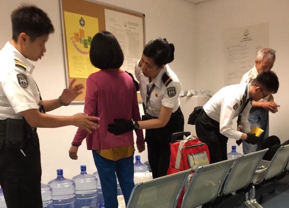 Airport security officers perform a thorough pat-down of a Taiwanese Falun Gong practitioner before forcing her to board a return flight to Taiwan. (Radio Free Asia)