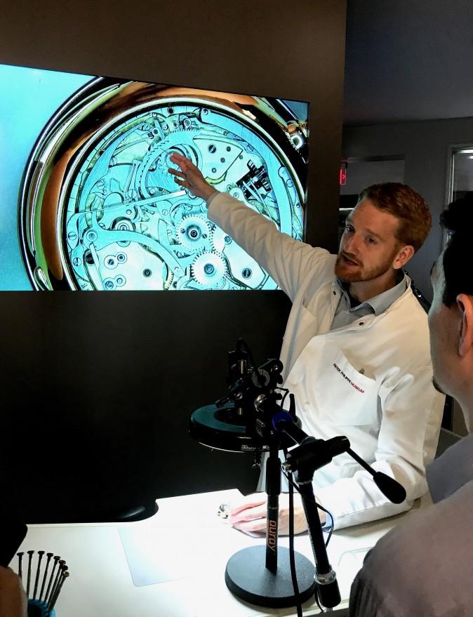 A watchmaker explains how the movement of an antique mechanical pocket watch works at the exhibition on July 13, 2017. (Milene Fernandez/The Epoch Times)