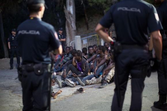 Police stand around a group of African migrants after they crossed the border fence from Morocco to Spain's North African enclave of Ceuta, Spain August 1, 2017. (Reuters/Jesus Moron)