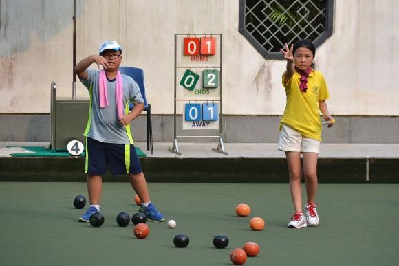 Jason Wong (right) and Summer Shen indicating to their skipper of the situation during the final of the 8-11 years old group at the U25 Age Group Lawn Bowls Competition. Shen, the defending champion, won three shots in this end but eventually lost 10:5. (Stephanie Worth)