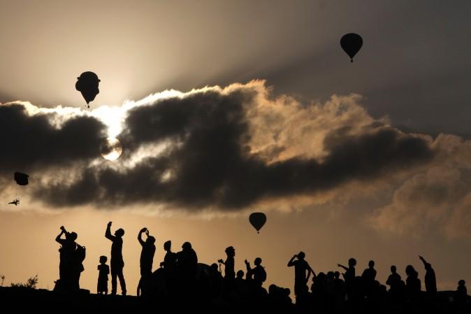 People watch and take photos of hot air balloons flying during the Gilboa Hot Air Balloon Festival near Kibbutz Ein Harod, Israel, on Aug. 4, 2017. (MENAHEM KAHANA/AFP/Getty Images)