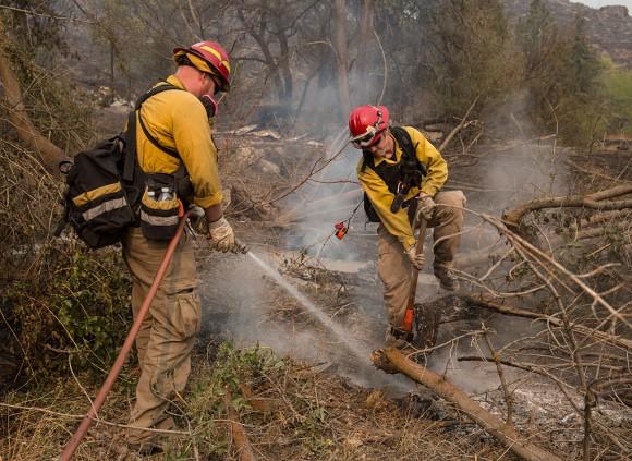 Firefighters extinguish hotspots after a wildfire, swept through the area on Aug. 22, 2015, near Okanogan, Wash. (Stephen Brashear/Getty Images)