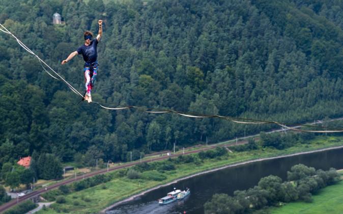 Slackliner Kai is blindfolded as he walks on a highline during an outdoor and trend sports festival over the Elbe river at the Koenigstein Fortress in Koenigstein, eastern Germany, on Aug. 5, 2017. (ARNO BURGI/AFP/Getty Images)