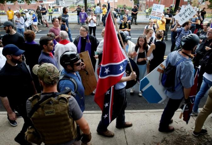 A white supremacists carries the Confederate flag as he walks past counter demonstrators in Charlottesville, Virginia, U.S., August 12, 2017. REUTERS/Joshua Roberts