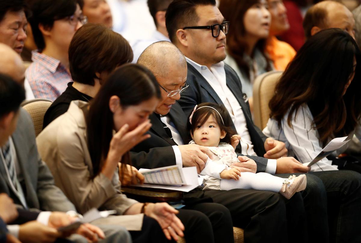 Pastor Hyeon Soo Lim, who returned to Canada from North Korea after the DPRK released Lim on August 9, after being held for 31 months, holds his granddaughter beside his son James, at the Light Presbyterian Church in Mississauga, Ontario, Canada on August 13, 2017. (REUTERS/Mark Blinch)