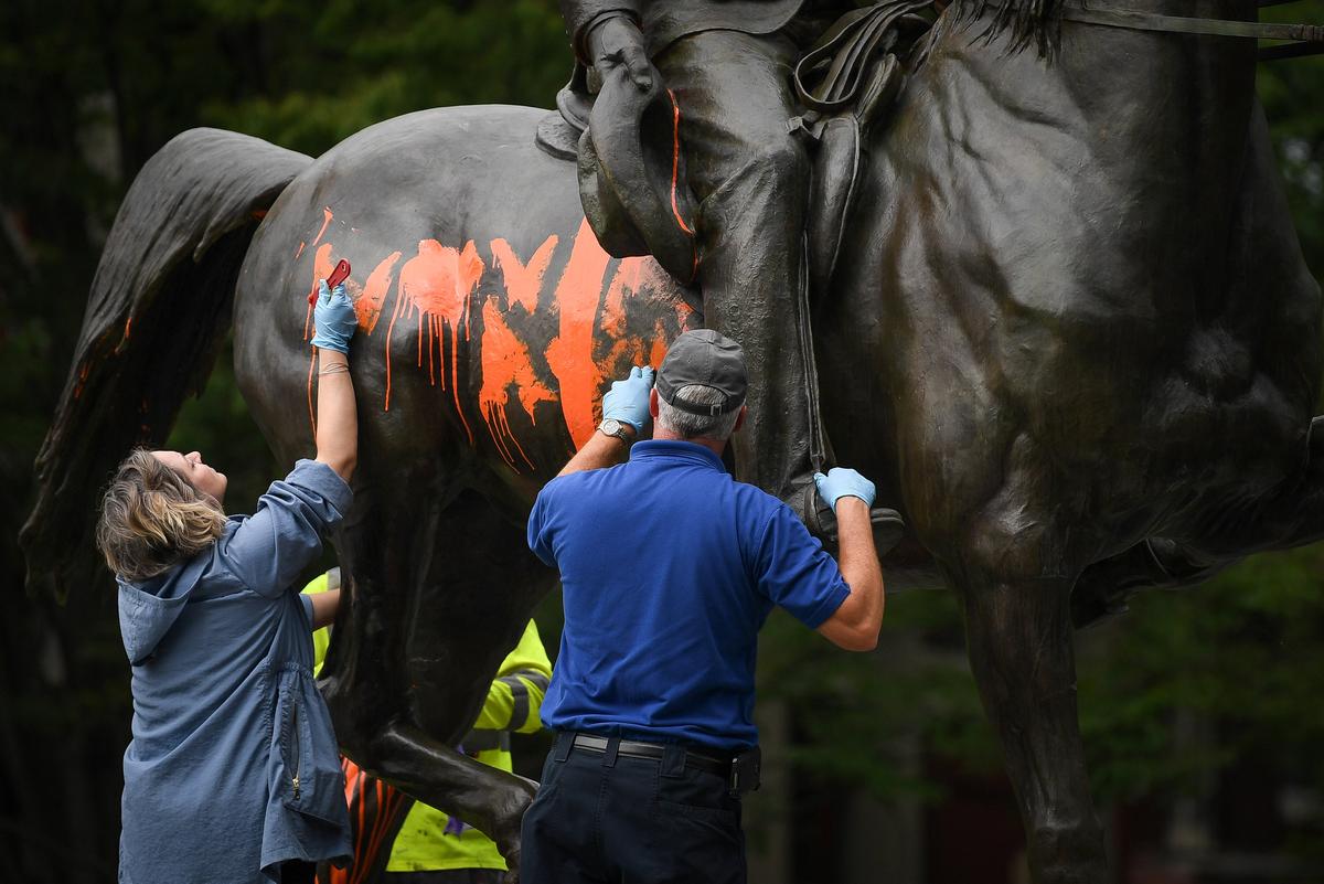 Municipal workers attempt to remove paint from a monument dedicated to Confederate soldier John B. Castleman that was vandalized late Saturday night in Louisville, Kentucky, U.S., August 14, 2017. (REUTERS/Bryan Woolston)