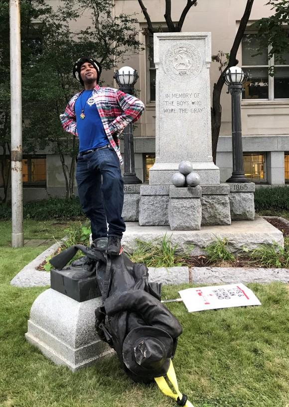 A man who was marching in a protest poses on the toppled statue of a Confederate soldier in front of the old Durham County Courthouse in Durham, North Carolina, on Aug. 14, 2017. (REUTERS/Kate Medley)