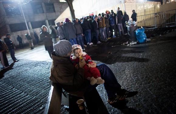 A man from Syria feeds his daughter as asylum seekers line up in front of the State Office of Health and Social Affairs (LAGeSo) registration center in Berlin on Dec. 21, 2015. (Kay Nietfeld/AFP/Getty Images)