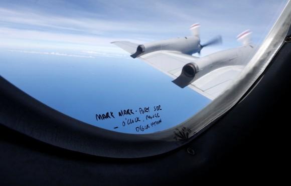 Hand-written notes on how a crew member should report the sighting of debris in the southern Indian Ocean is pictured on a window aboard a Royal New Zealand Air Force P-3K2 Orion aircraft searching for missing Malaysian Airlines flight MH370, March 22, 2014. (Reuters/Jason Reed/File Photo)