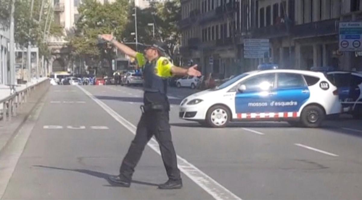 A still image from video shows a police officer gesturing while walking across a road, after a van crashed into people in the centre of Barcelona, Spain on Aug. 17, 2017. (REUTERS TV via REUTERS)