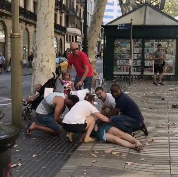 People help an injured woman lying on the ground after a van crashed into pedestrians near the Las Ramblas avenue in central Barcelona, Spain August 17, 2017, in this still image from a video obtained from social media. (Courtesy of Carlos Tena Gallardo/via REUTERS)