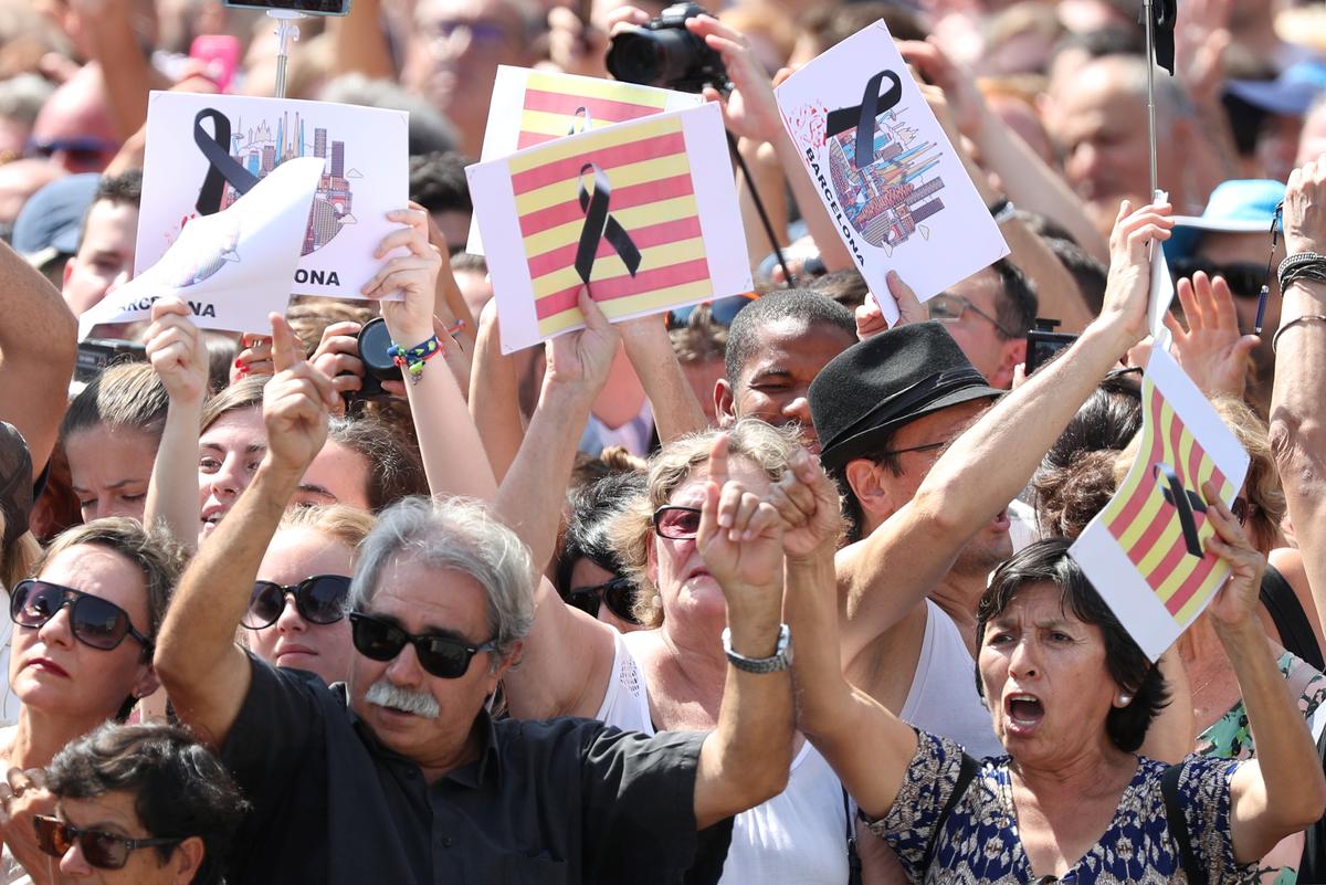 People hold banners as they observe a minute of silence in Placa de Catalunya, a day after a van crashed into pedestrians at Las Ramblas in Barcelona, Spain August 18, 2017. (REUTERS/Sergio Perez)
