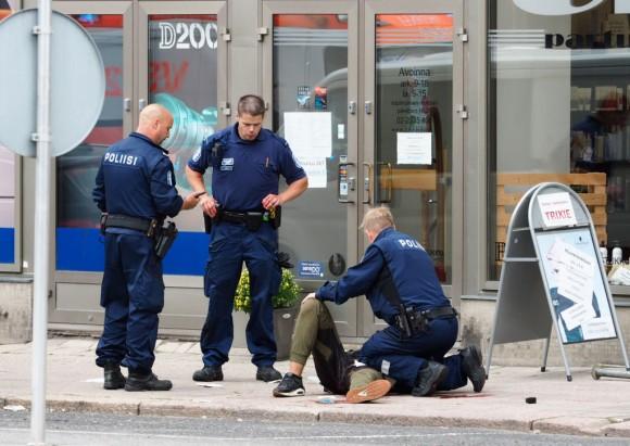 Police officers stand next to a person lying on the pavement in the Finnish city of Turku where several people were stabbed on August 18, 2017. (KIRSI KANERVA/AFP/Getty Images)