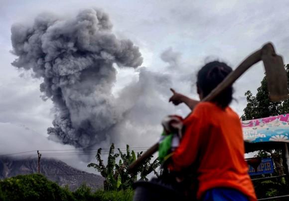 An Indonesian villager gestures as Mount Sinabung volcano spews thick volcanic ash, in Karo, North Sumatra, on July 8, 2017. (AFP/Getty Images)