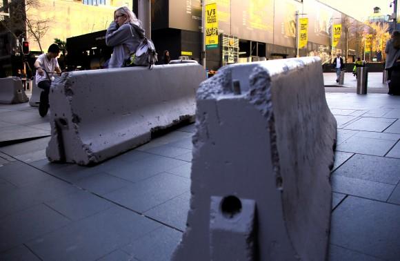 A woman rests on a concrete block that was placed by authorities as extra security measures at Sydney's Martin Place in Australia, July 18, 2017. (Reuters/David Gray)