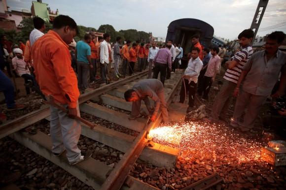 A railway worker repairs the tracks next to derailed coaches of a passenger train, at the site of an accident in Khatauli, in the northern state of Uttar Pradesh, India August 20, 2017. (Reuters/Adnan Abidi)