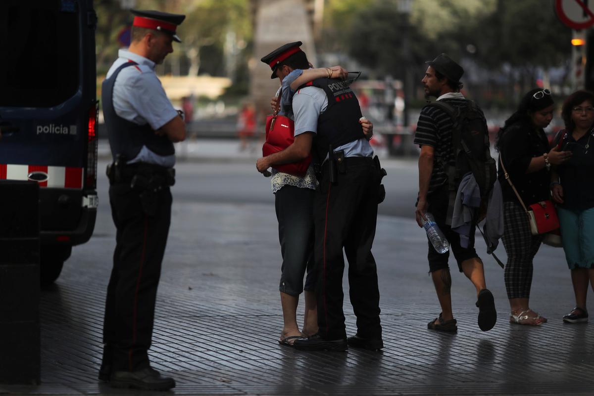 Pilar Revilla, 75, hugs a Catalan Mossos d'Esquadra officer after visiting an impromptu memorial where a van crashed into pedestrians at Las Ramblas in Barcelona, Spain on August 20, 2017. (REUTERS/Susana Vera)