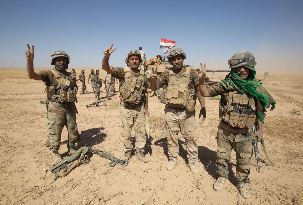 Fighters from the Hashed al-Shaabi (Popular Mobilisation) paramilitaries gesture to the camera as they prepare to advance towards the city of Tal Afar, the main remaining stronghold of the Islamic State group, after the government announced the beginning of an operation to retake it from the jihadists, on August 20, 2017. (AHMAD AL-RUBAYE/AFP/Getty Images)