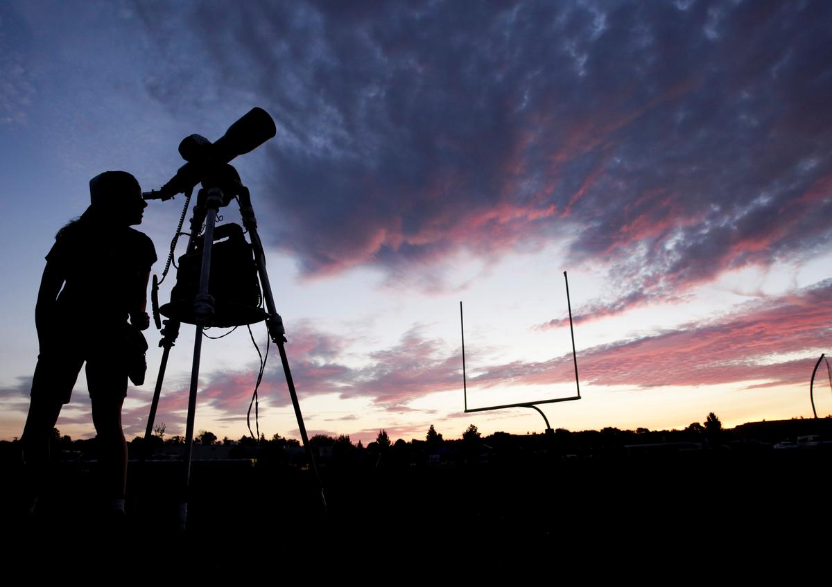 A woman looks through a telescope on the football field at Madras High School the evening before a solar eclipse in Madras, Oregon on Aug.20, 2017. (REUTERS/Jason Redmond)