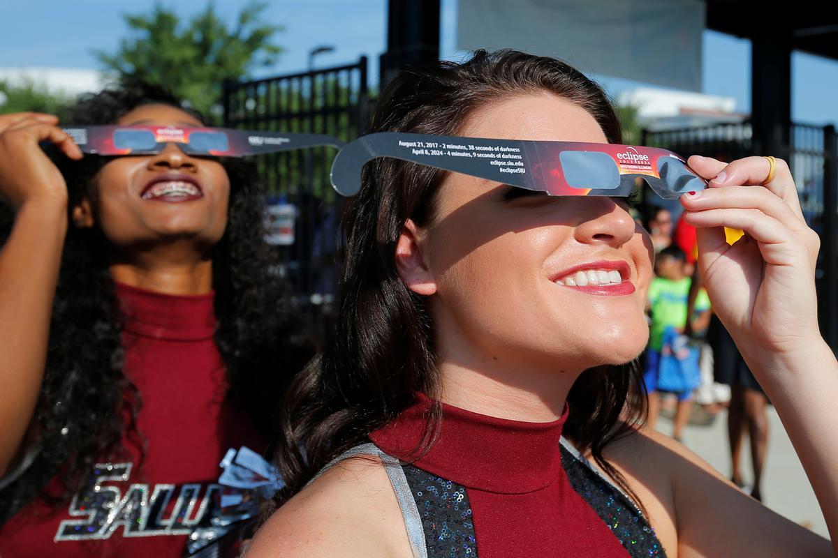 Cheerleaders use solar viewing glasses before welcoming guests to the football stadium to watch the total solar eclipse at Southern Illinois University in Carbondale, Ill., on Aug. 21, 2017. (REUTERS/Brian Snyder)