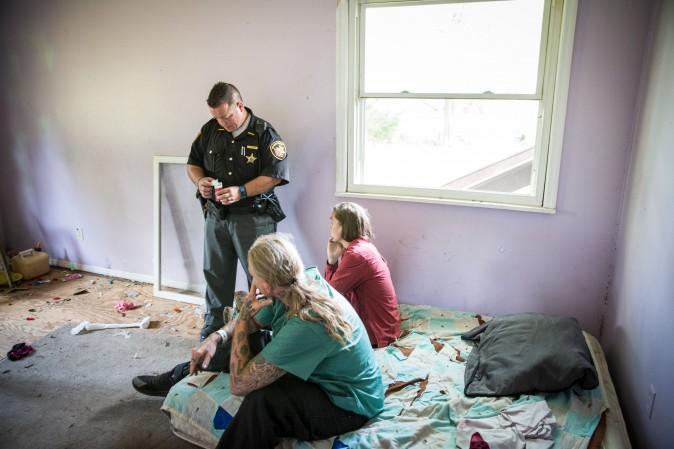 Deputy Sheriff Andy Teague, speaks with two people who have allegedly been using drugs inside an abandoned home in Montgomery County, Ohio, on Aug. 3, 2017. (Benjamin Chasteen/The Epoch Times)