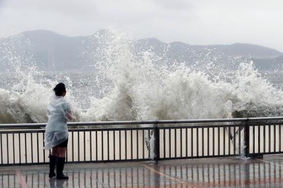 A woman stands beside a big wave on a waterfront Typhoon Hato hitting in Hong Kong, China August 23, 2017. (Reuters/Tyrone Siu)
