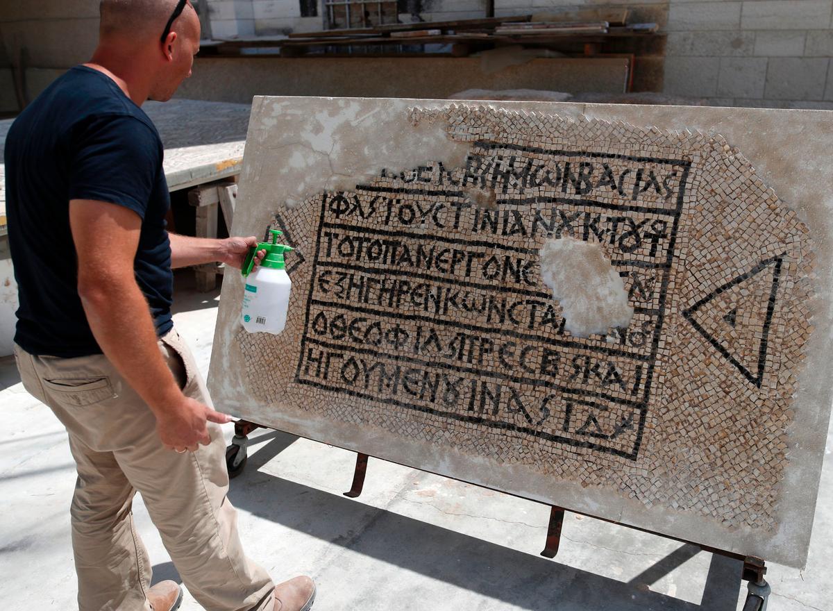 An archaeologist works on part of a 1,500-year-old mosaic floor bearing the names of Byzantine Emperor Justinian, at the Rockefeller Museum in Jerusalem, on August 23, 2017, after they unearth a portion of ancient mosaic near the city's Damascus Gate.<br/>(AHMAD GHARABLI/AFP/Getty Images)