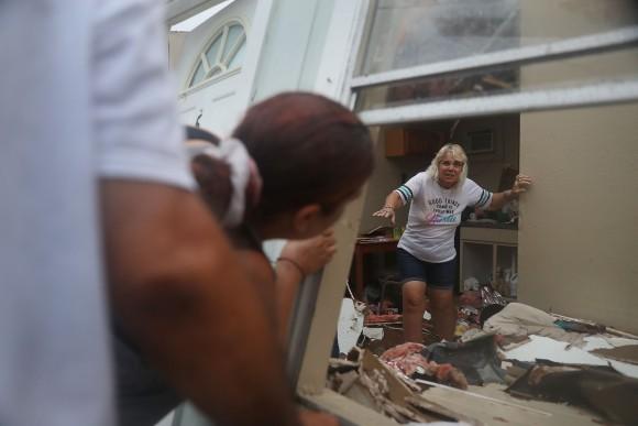 Donna Raney makes her way out of the wreckage of her home as Daisy Graham tells her she will help her out of the window after Hurricane Harvey destroyed the apartment on Aug. 26, 2017, in Rockport, Texas. Donna was hiding in the shower after the roof blew off and the walls of her home caved in by the winds from Hurricane Harvey. (Joe Raedle/Getty Images)